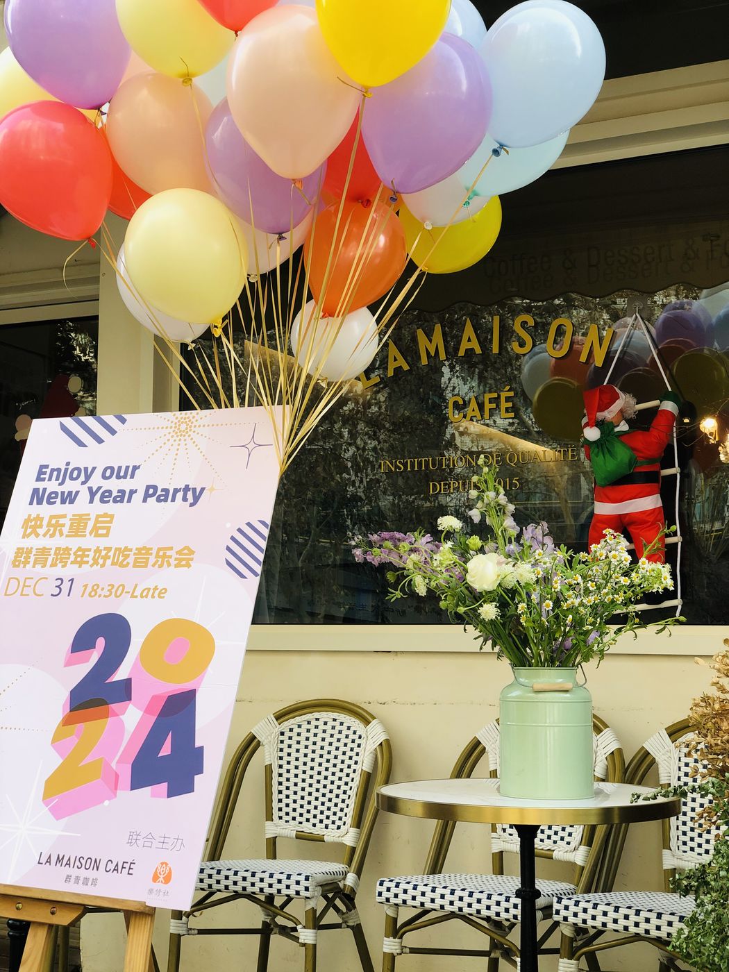 群青咖啡馆门口的新年气球与活动海报，橱窗上写着 LA MAISON CAFÉ 与 INSTITUTION DE QUALITÉ DEPUIS 2015