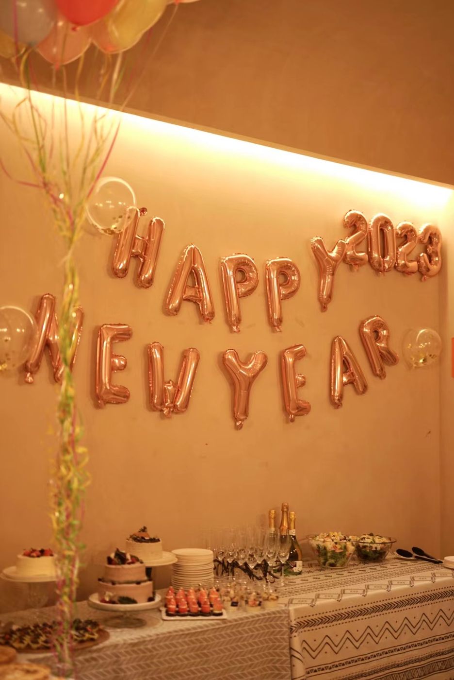 群青咖啡馆的跨年派对现场：金色 HAPPY NEW YEAR 气球、蛋糕与香槟，长桌上摆满茶点